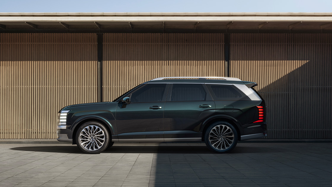 The all-new PALISADE side view, in front of a wall