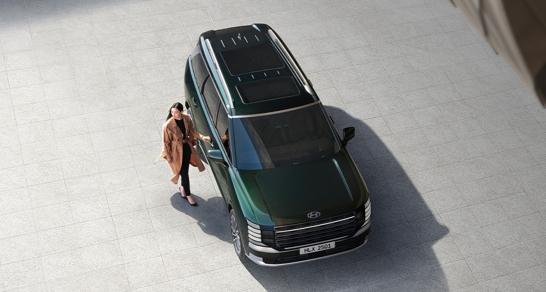 A woman standing next to the all-new PALISADE