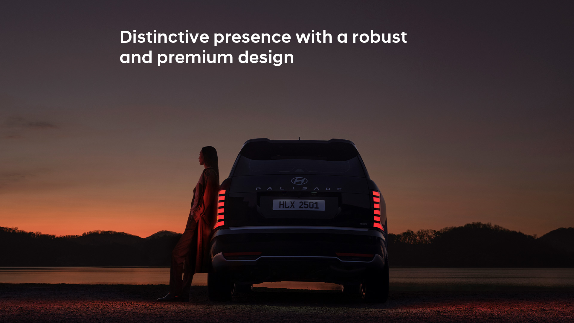 A woman leaning on the side of the all-new PALISADE, gazing at the sunset