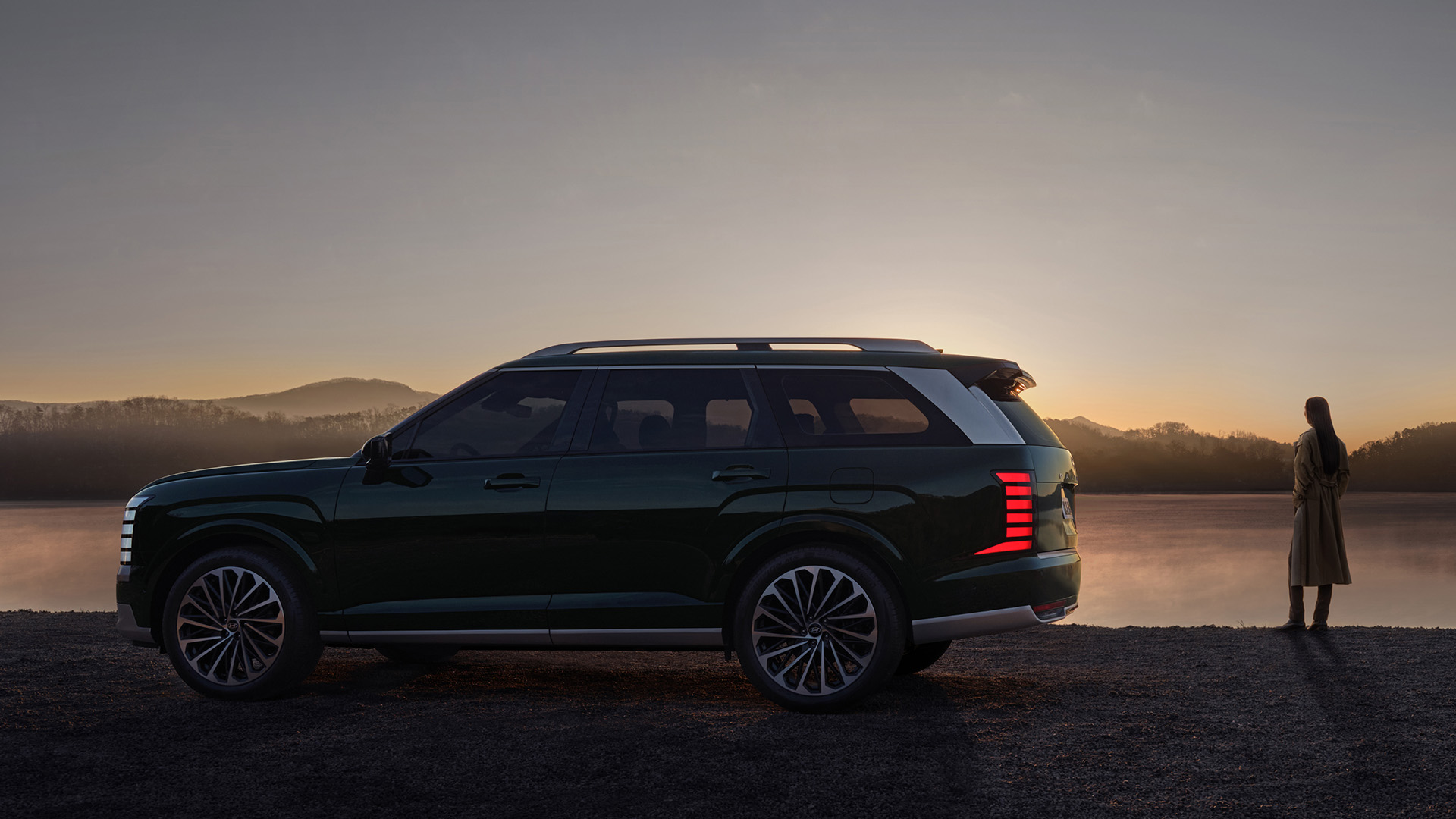 The all-new PALISADE side view, and a woman standing near the vehicle.