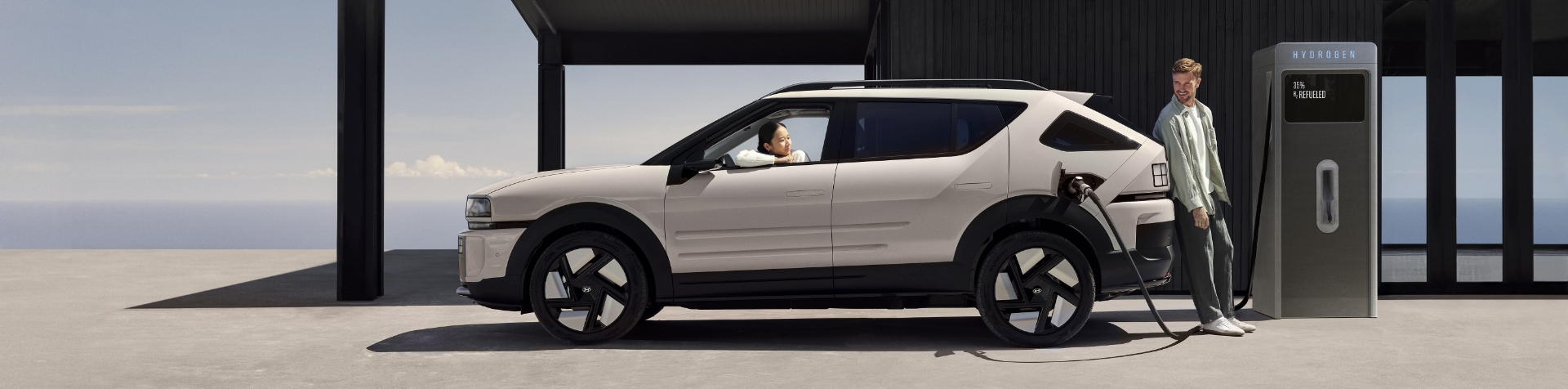 A seated woman looks out the window of the all-new Hyundai NEXO while it is charging