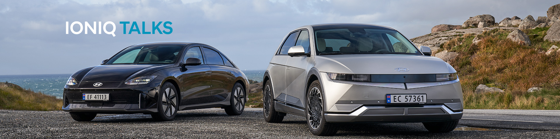 A black Hyundai IONIQ 6 and a gray Hyundai IONIQ 5 parked on the edge of a racetrack.