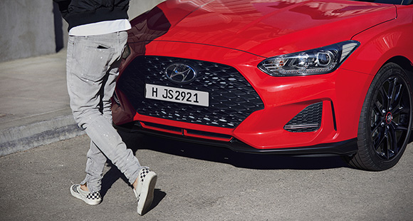 Left side front view of red veloster parking on the road