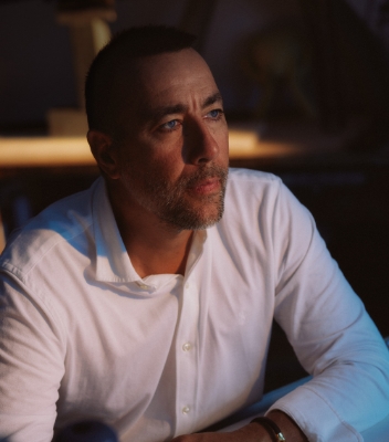 Close-up portrait of Team Century’s Lorenzo Quinn wearing a white buttoned-up shirt looking thoughtfully into the distance.